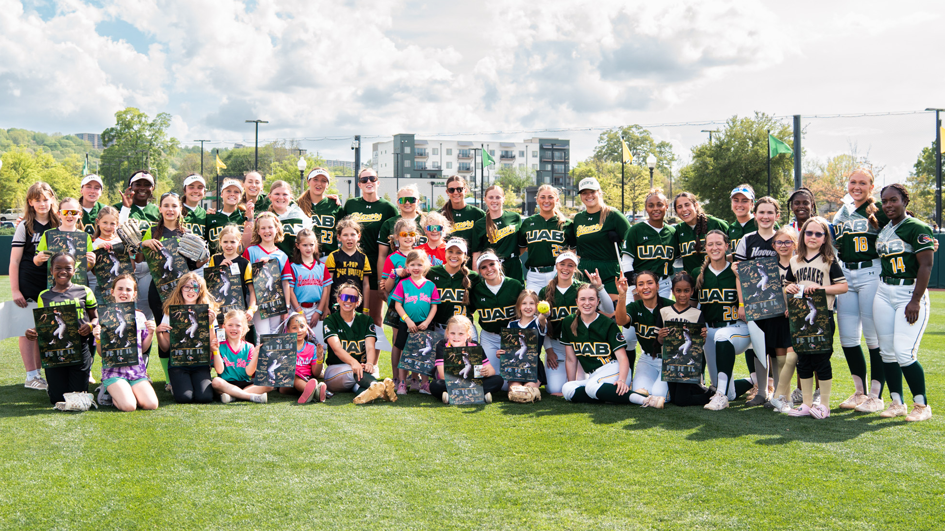 Youth group posing with UAB Softball team after an autogrpah session